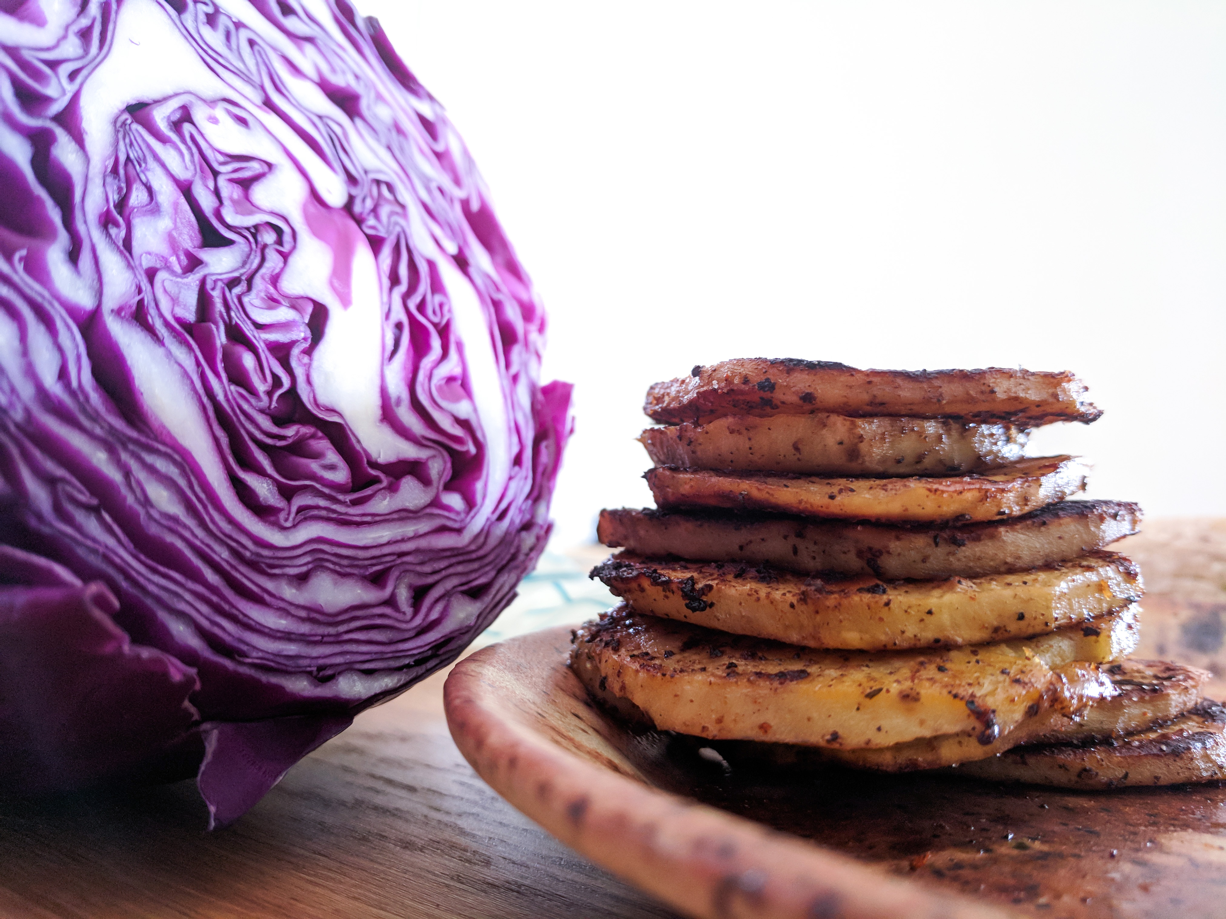 Red cabbage sliced open next to BBQ grilled sweet potato slices.